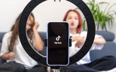 trending sounds, two girls making a tiktok video on a sofa with phone in a holder and a ring light